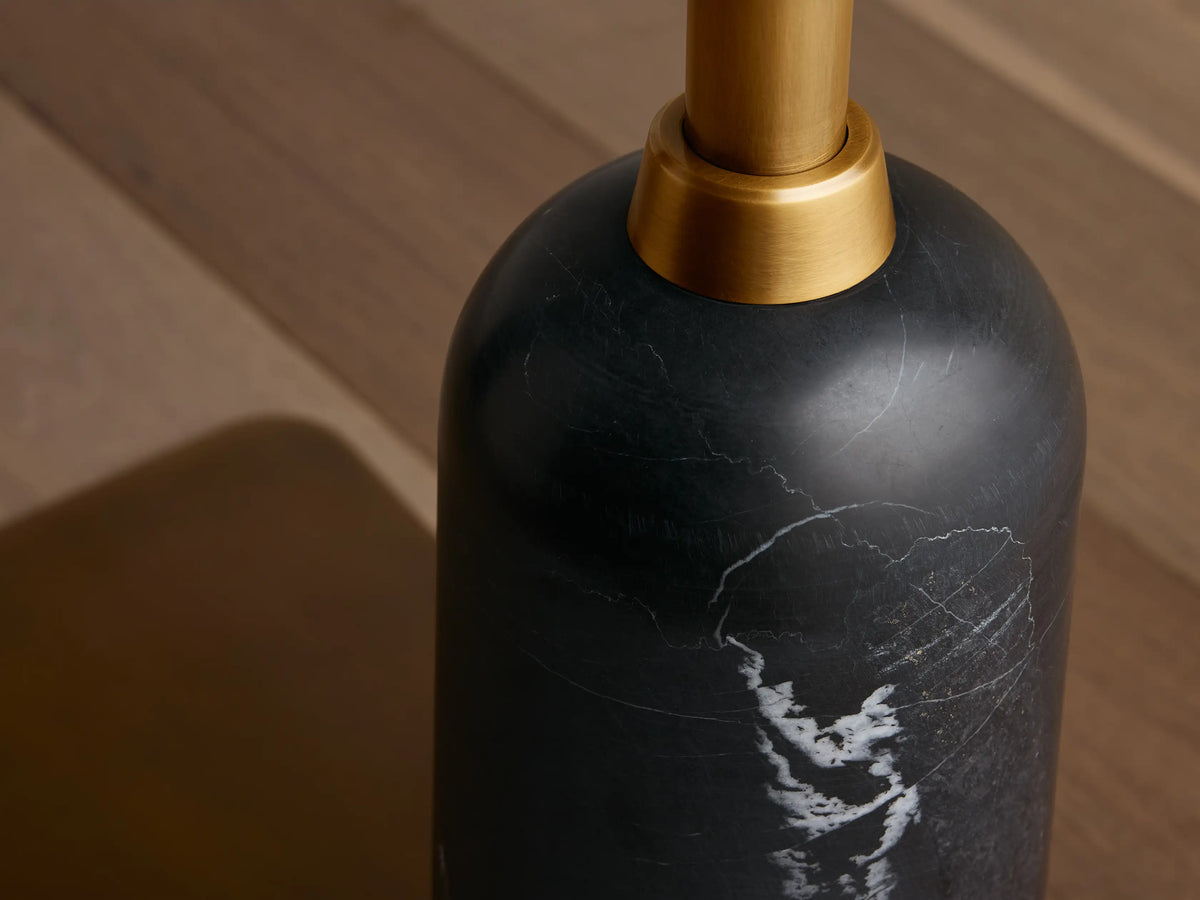 Close-up of Christie Floor Lamp's black marble base with white veining and brass-finished steel stem against wood floor.