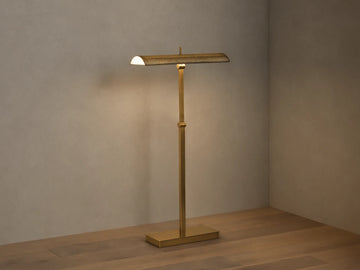 Abel Metal Floor Lamp: Upright, brass finish, rectangular base, long perforated shade emitting warm LED light. Beige wall, wood floor.
