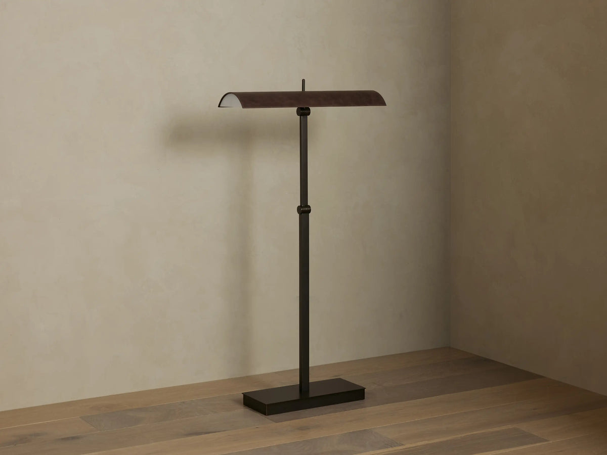 Abel Leather Floor Lamp: dark bronze finish, horizontal leather shade emitting warm LED light, stands on a wood floor.