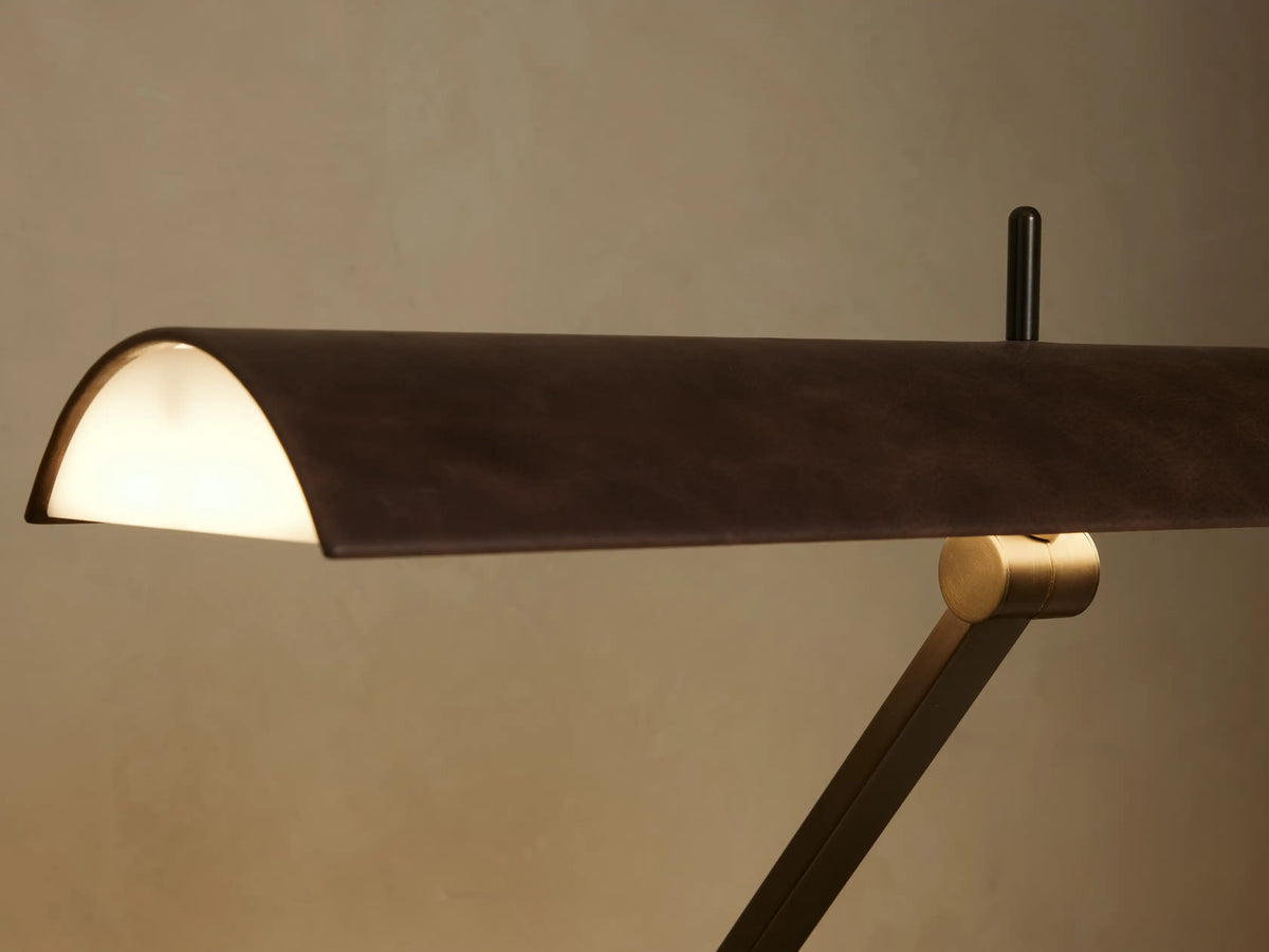 Abel Leather Floor Lamp with dark bronze steel base & stand, brown leather-wrapped curved shade, against a neutral wall & wood floor.