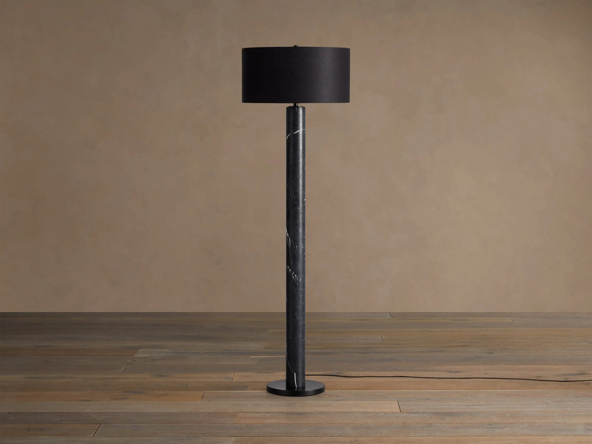 Brixton Floor Lamp with a black marble base & pole, topped by a dark brown drum shade, standing on a wooden floor.