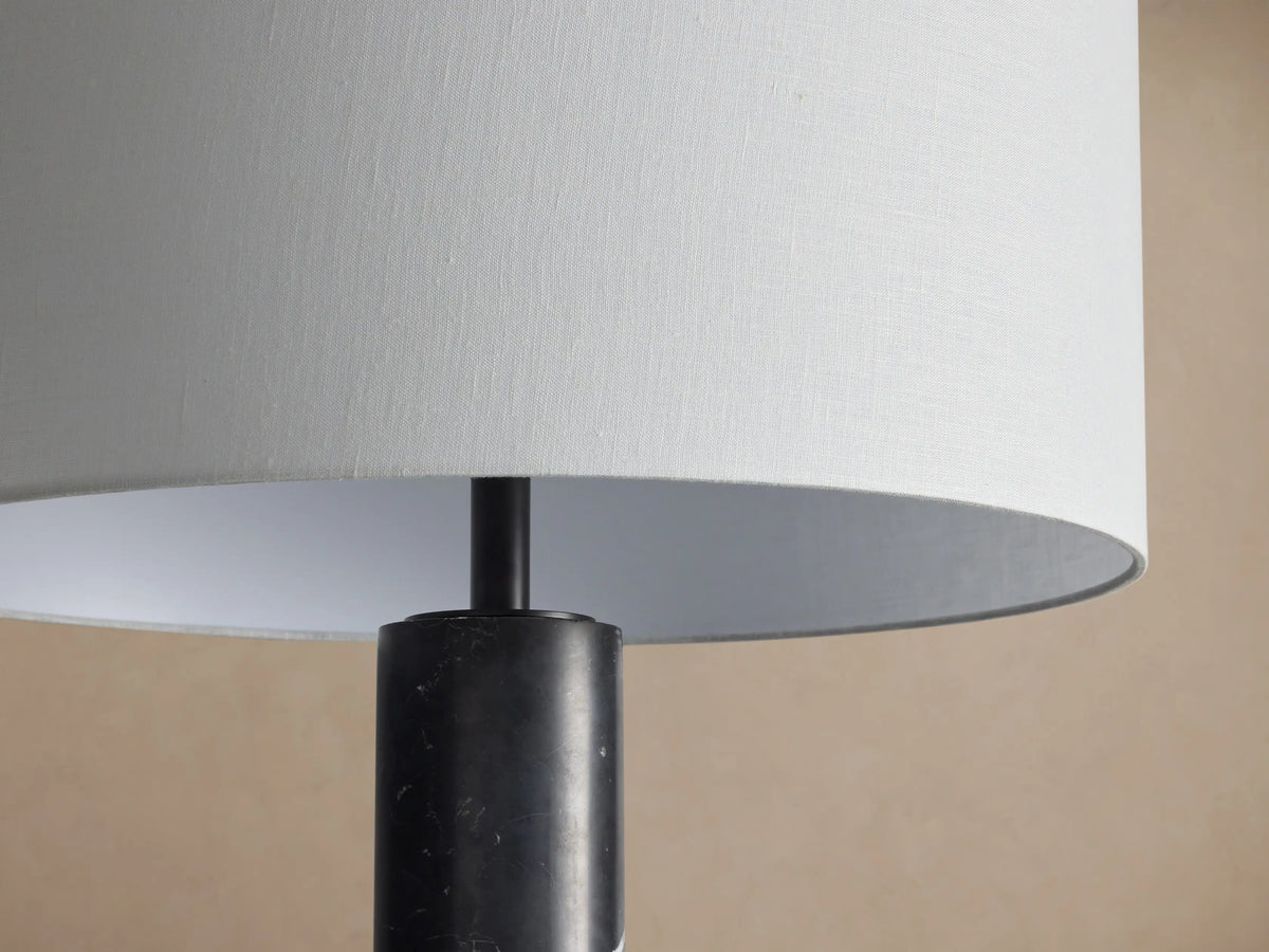 Brixton Floor Lamp: tall, dark marble column with white veins, topped by a simple white drum shade, on wood floor.