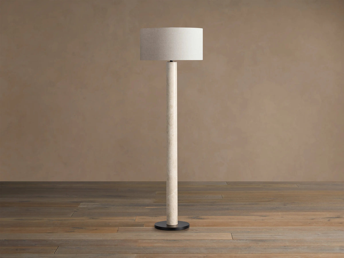 Brixton Floor Lamp, tall and slender, with a natural cream marble post, black circular base, and light beige fabric drum shade.