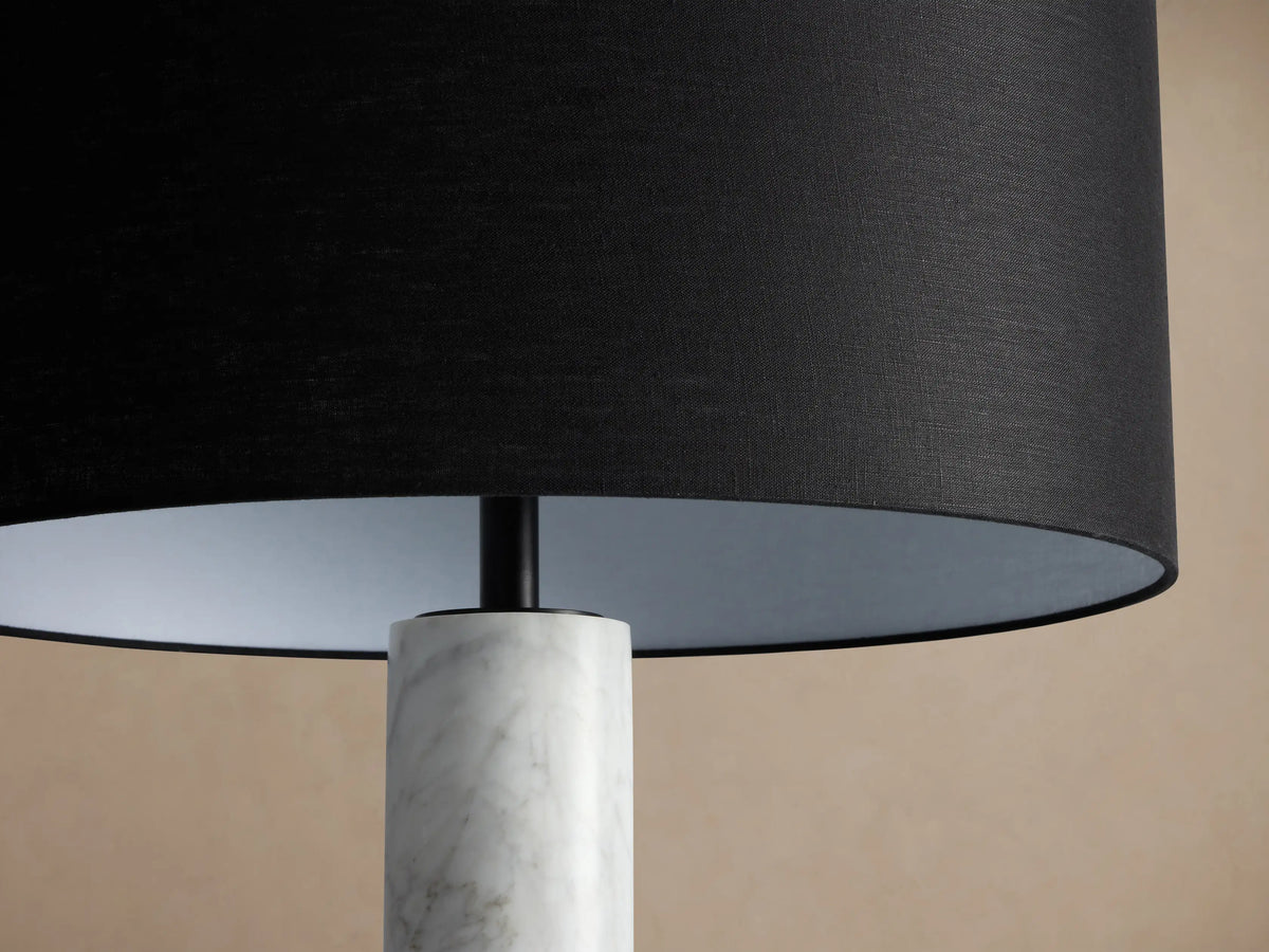 Brixton Floor Lamp: Tall, elegant, with white marble column, black drum shade, and round black base on a wood floor.