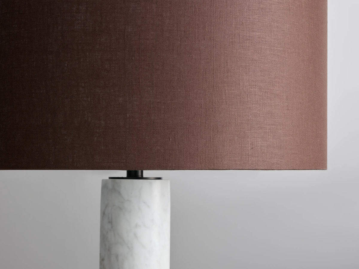 Brixton Floor Lamp with brown cylindrical shade, white marble column, black circular base, on wooden floor against neutral wall.