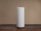 Kelby Outdoor Rechargeable Lamp, a tall, lit, cylindrical white alabaster lamp with natural patterns, on a dark wooden surface.