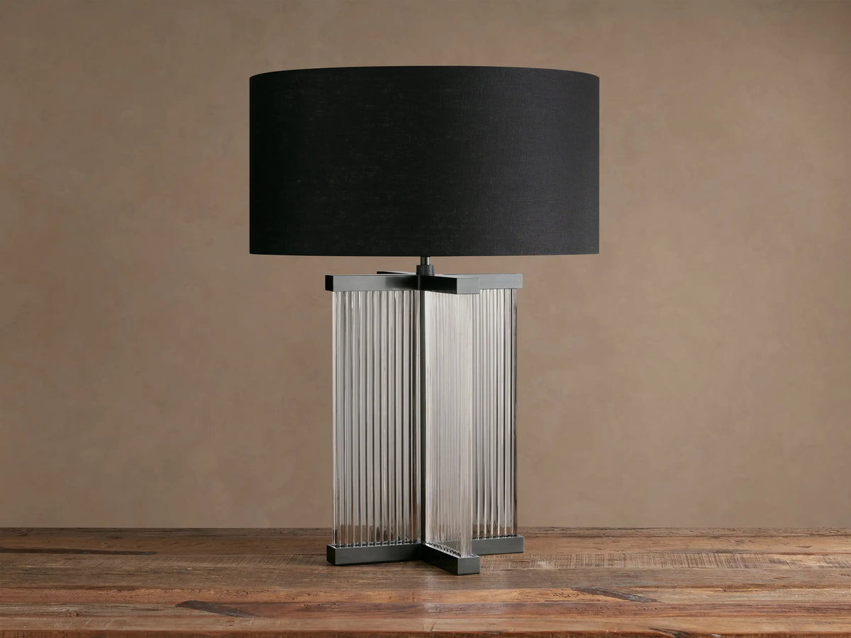 Delsie Table Lamp featuring a black drum shade atop a fluted clear glass column base with dark bronze-toned metal accents.