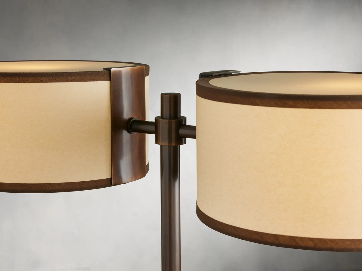 Daphne 2-Light Table Lamp with bronze finish, featuring two cream shades with brown trim, on round wooden table.