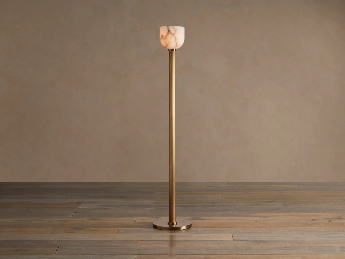 Illuminated Ansley Floor Lamp with a slender, antique brass stem & base, topped by a glowing, veined alabaster bowl shade.