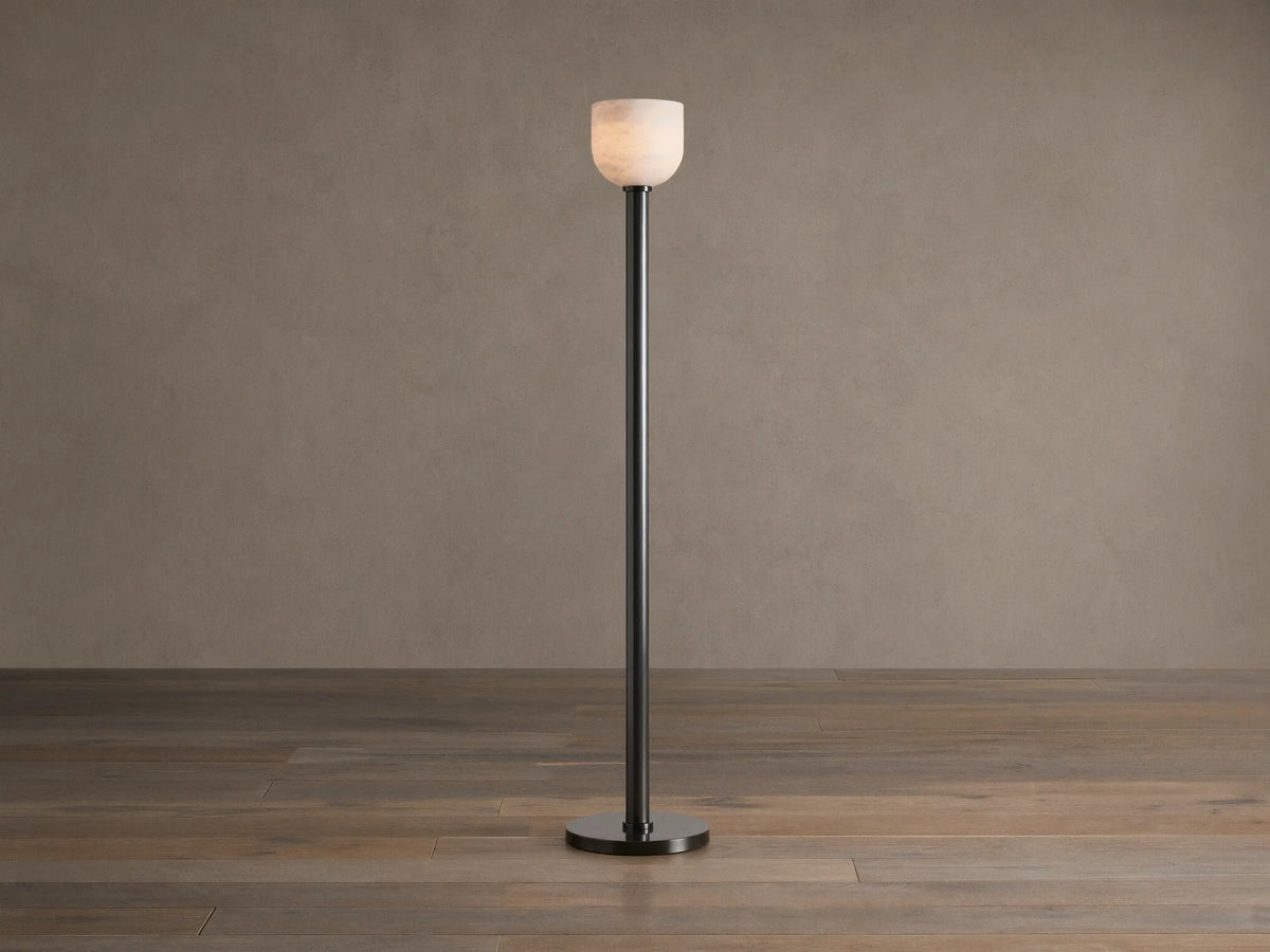 Ansley Floor Lamp: tall, dark steel pole and round base with an illuminated natural alabaster stone shade on a wooden floor.