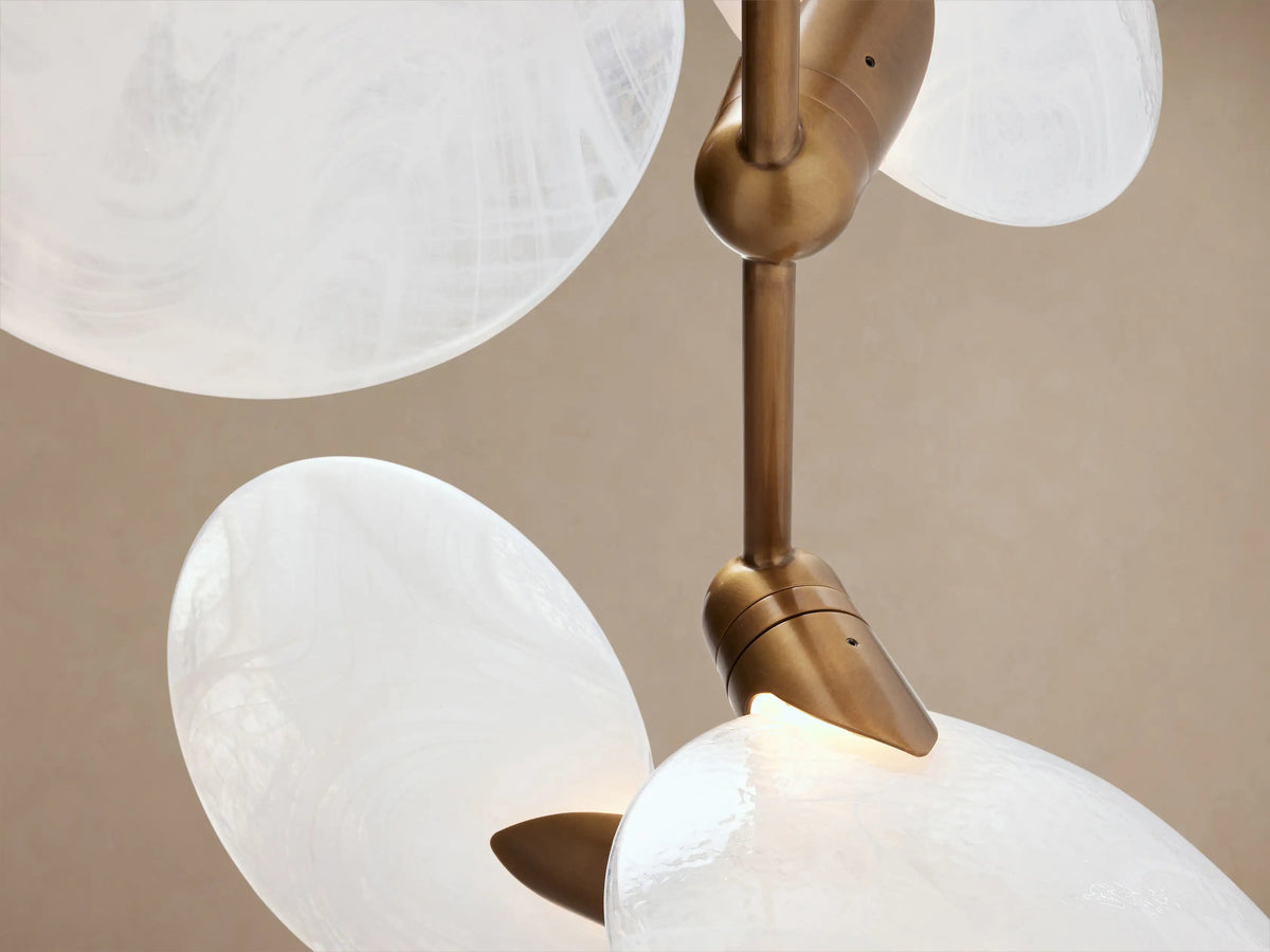 Lyla Floor Lamp: light travertine cone base, gold stem, and six white oval mouth-blown glass lights on wooden floor.
