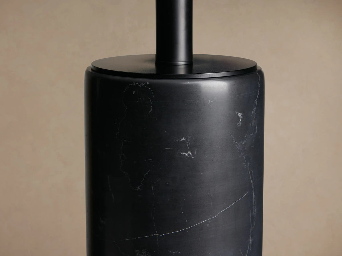 Brixton Table Lamp: Black marble cylindrical base, black fabric drum shade, centered on a rustic wooden table.