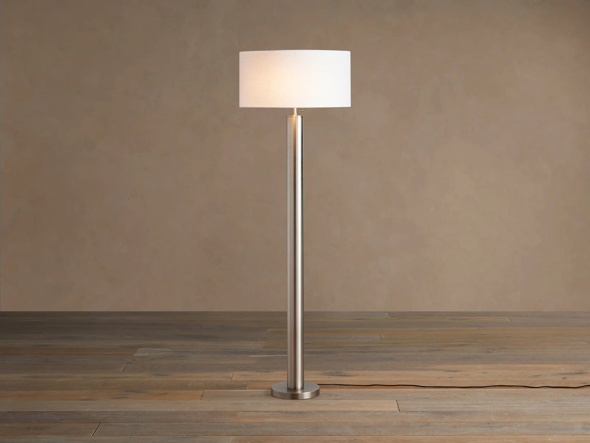 Linden Floor Lamp in Pewter: Tall, slender, metallic pewter finish pole and round base, with a white cylindrical linen shade.