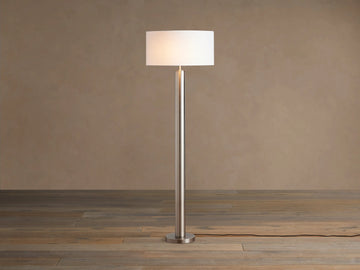 Linden Floor Lamp in Pewter: Tall, slender, metallic pewter finish pole and round base, with a white cylindrical linen shade.