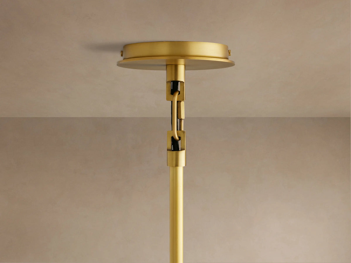 Linden Pendant with a light gray linen shade, viewed from below. Warm light illuminates the interior and a small brass-toned finial.