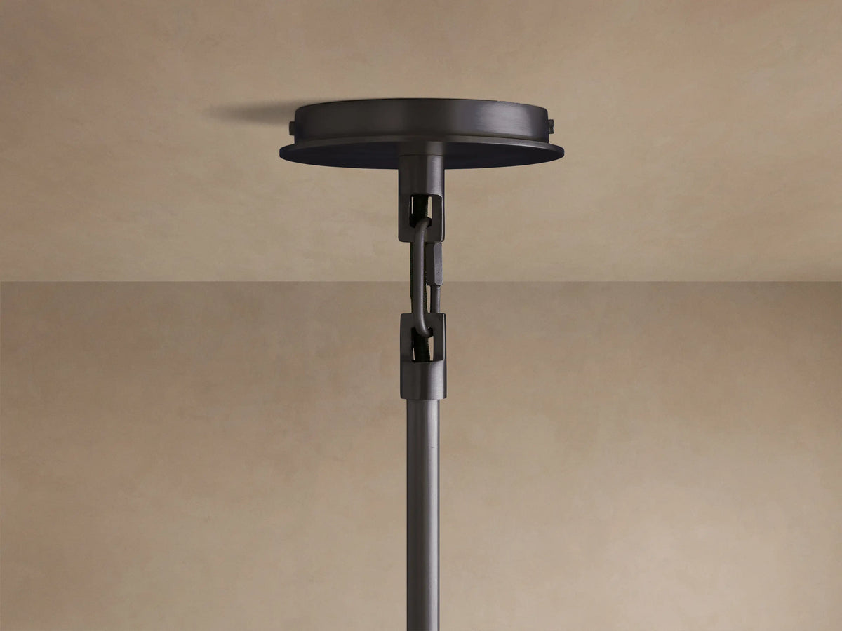 Linden Pendant with a light-colored, textured linen shade emitting warm light from its circular bottom. Black detail visible.