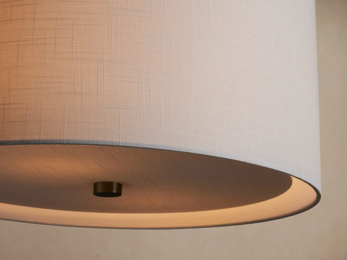 Linden Pendant with a light gray textured linen drum shade and brushed nickel hardware, hanging against a beige wall.
