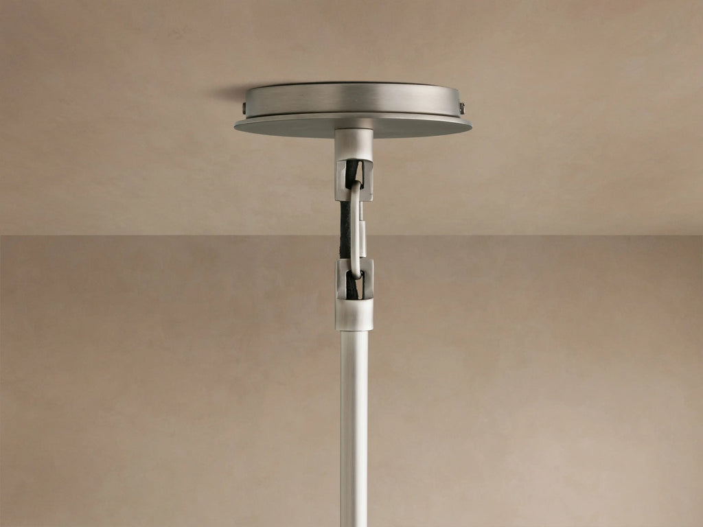 Close-up of a Linden Pendant, viewed from below, showing its light linen shade, warm interior glow, and dark metal accent.