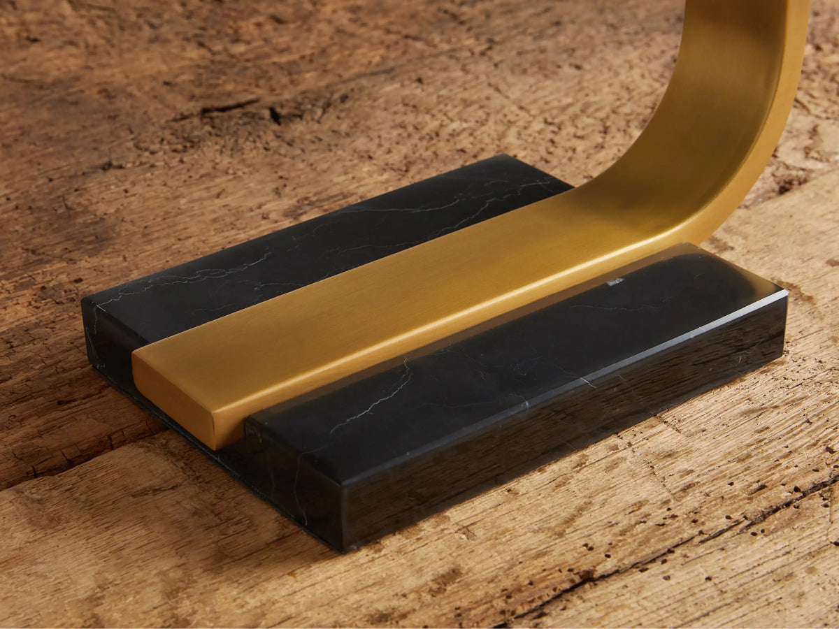 Karson Task Table Lamp, modern U-shaped design with brass finish and black marble base, on a rustic wood table.