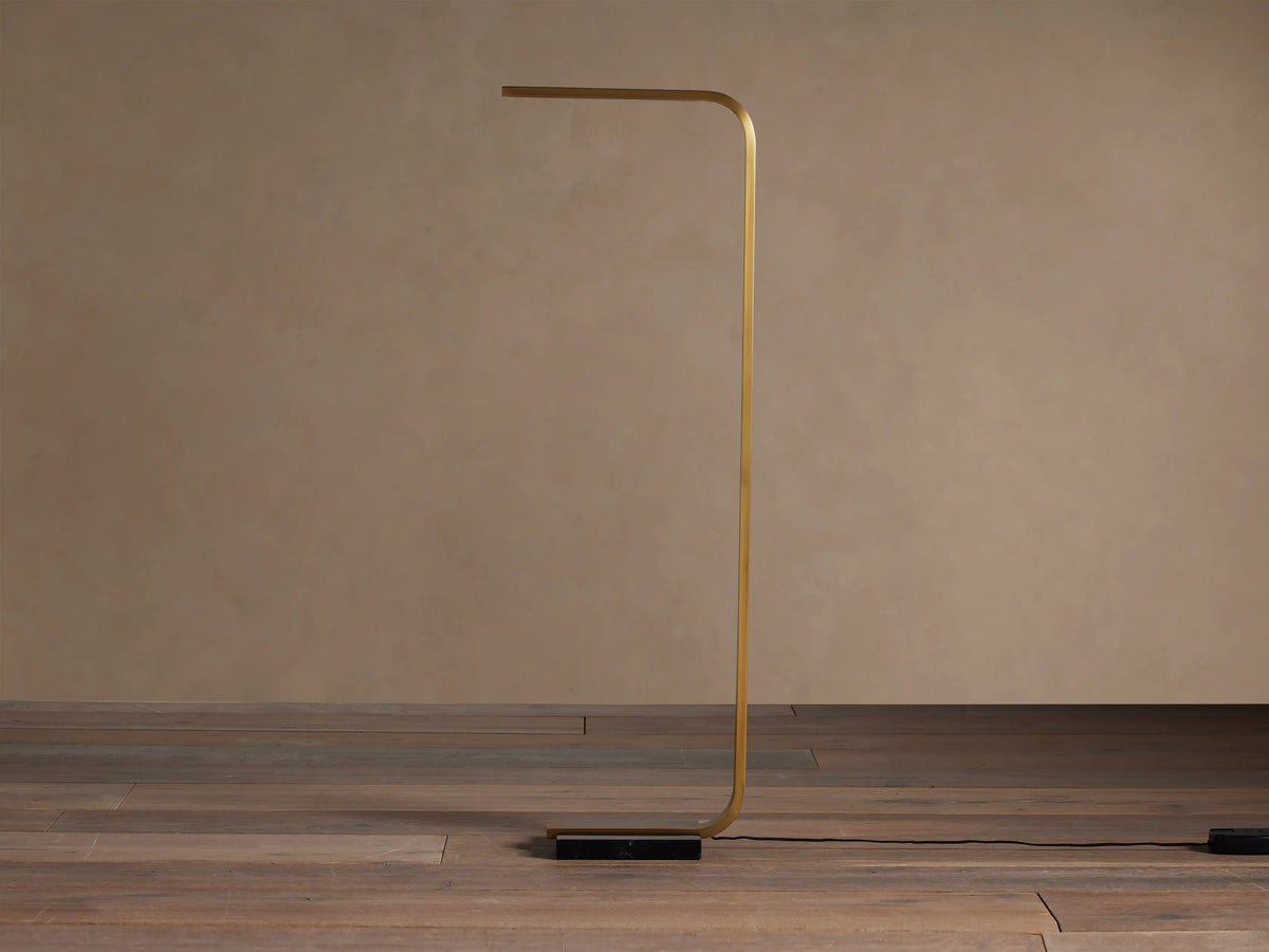 Modern golden brass Karson Task Floor Lamp with a bent rectangular frame, horizontal light bar, and black marble base.