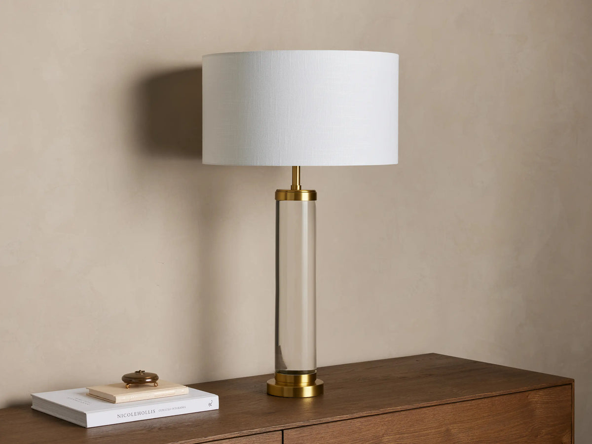 Front view of the Linden Crystal Table Lamp featuring a clear crystal column, brass-finished metal accents, and a white linen shade.