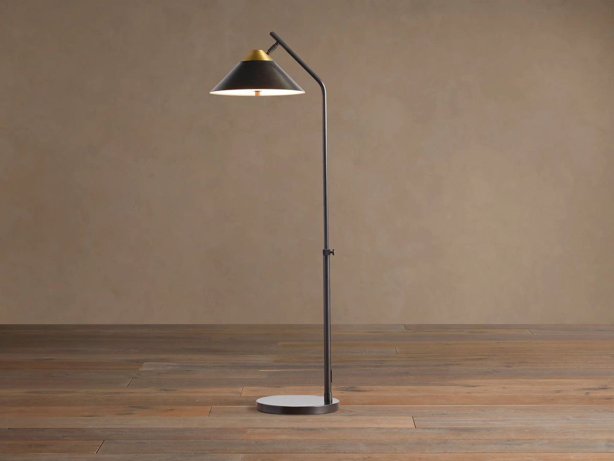 Marquee Bronze Task Floor Lamp. Dark bronze iron frame, conical shade with brass accent, adjustable pole, round base. Light on.
