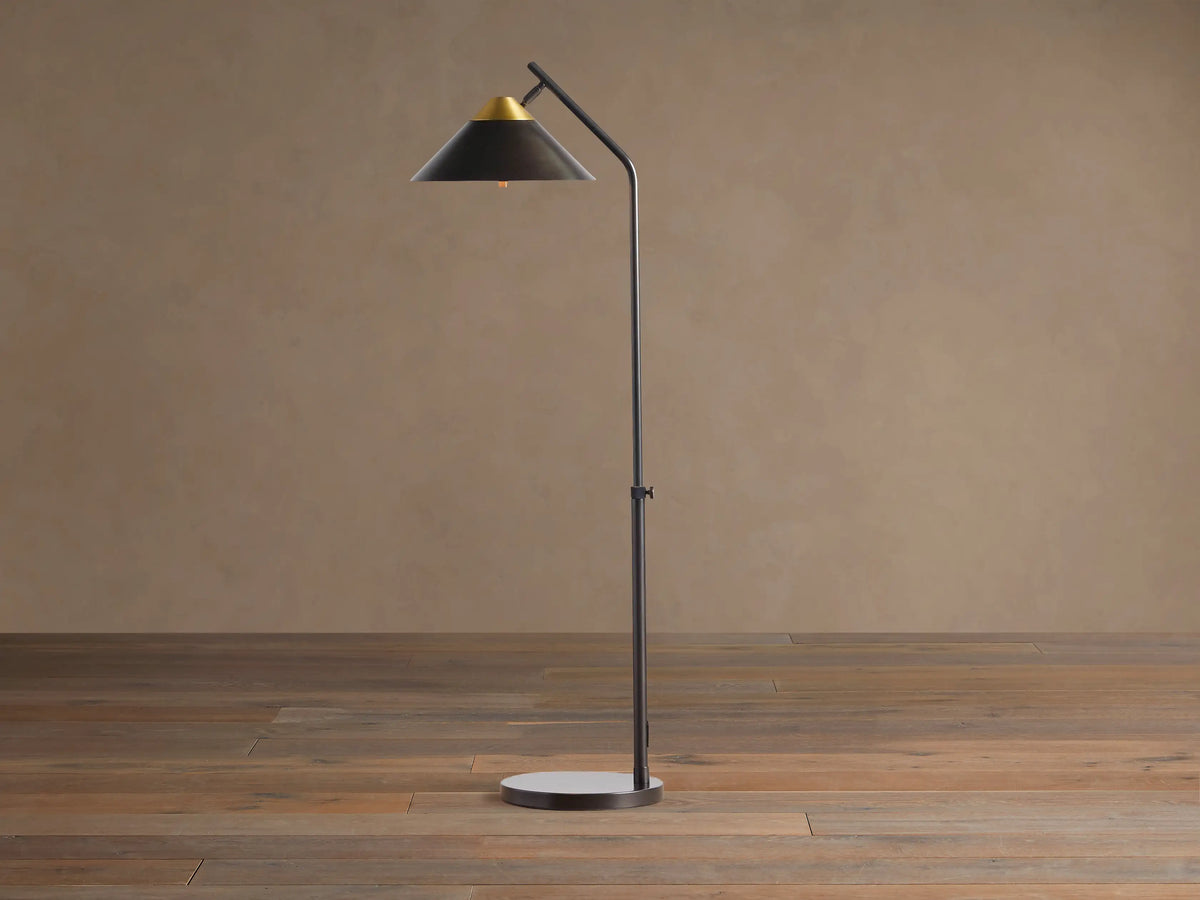 Marquee Bronze Task Floor Lamp. Dark bronze iron frame, conical shade with brass accent, adjustable pole, round base. Light on.