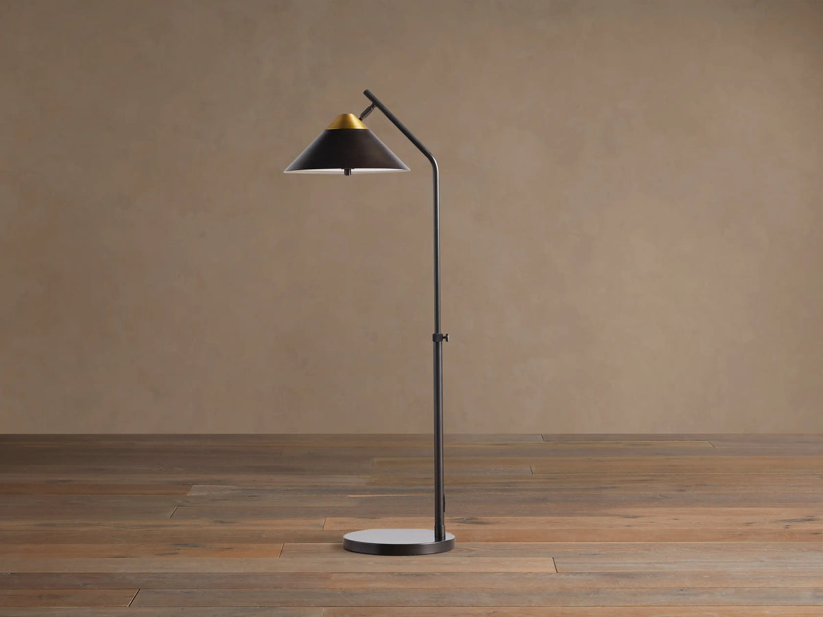 Close-up of Marquee Bronze Task Floor Lamp. Conical dark bronze shade with a brass top accent, angled on a dark arm.