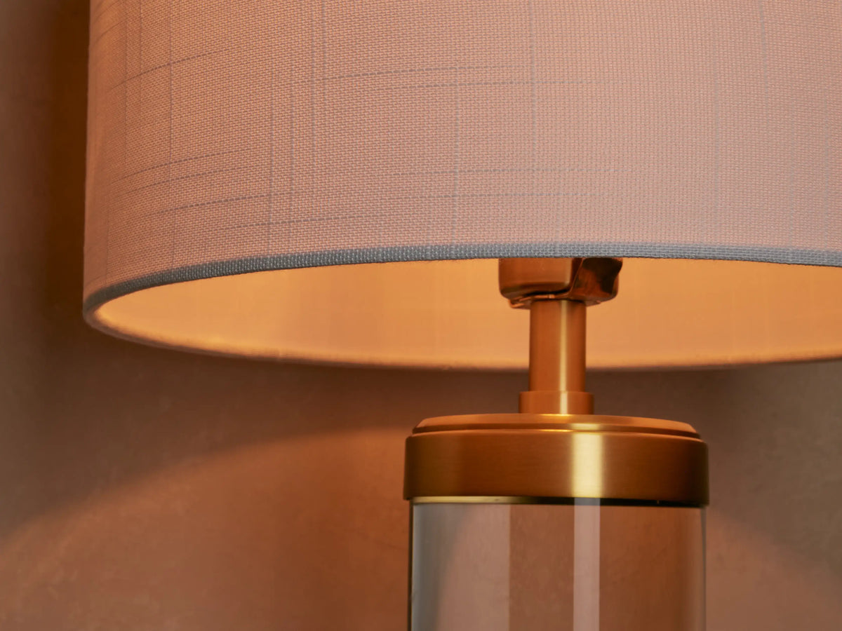 Linden Crystal Table Lamp, upright on wood table. White linen shade, clear crystal column, and brass-finished accents.