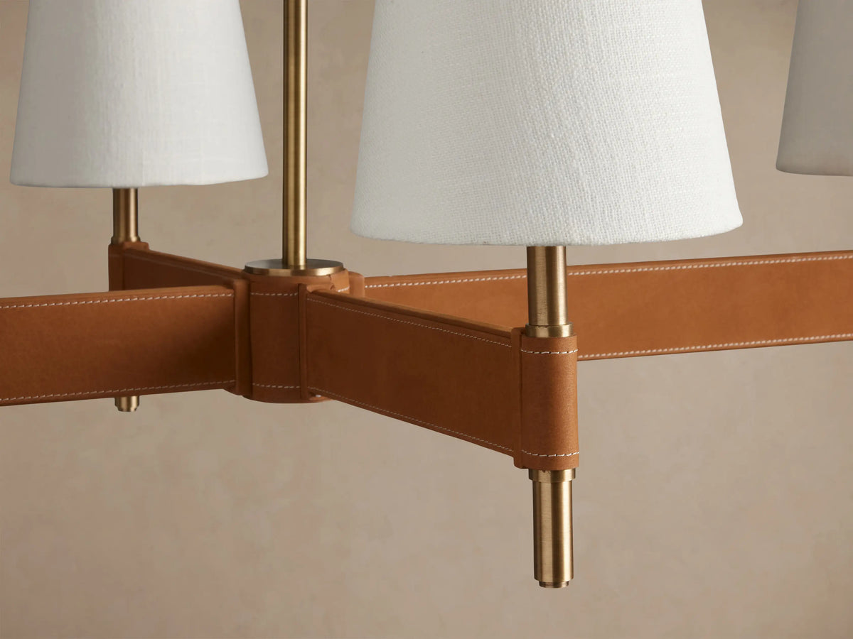 Hastings 6-Light Linear Chandelier with antiqued brass accents, brown leather-wrapped bar, and 6 white linen shades.