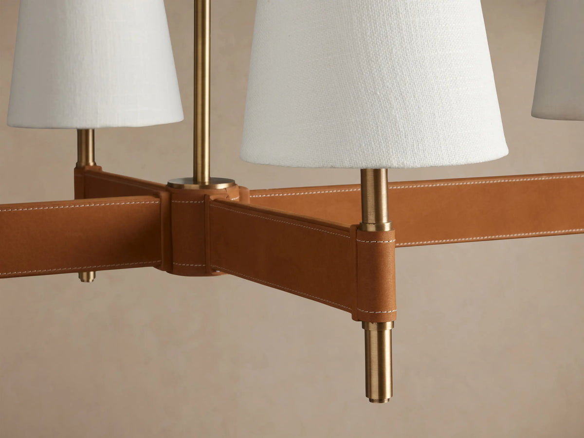 Hastings Linear Chandelier: 6 white linen shades on an antiqued brass & tan leather horizontal bar, suspended.