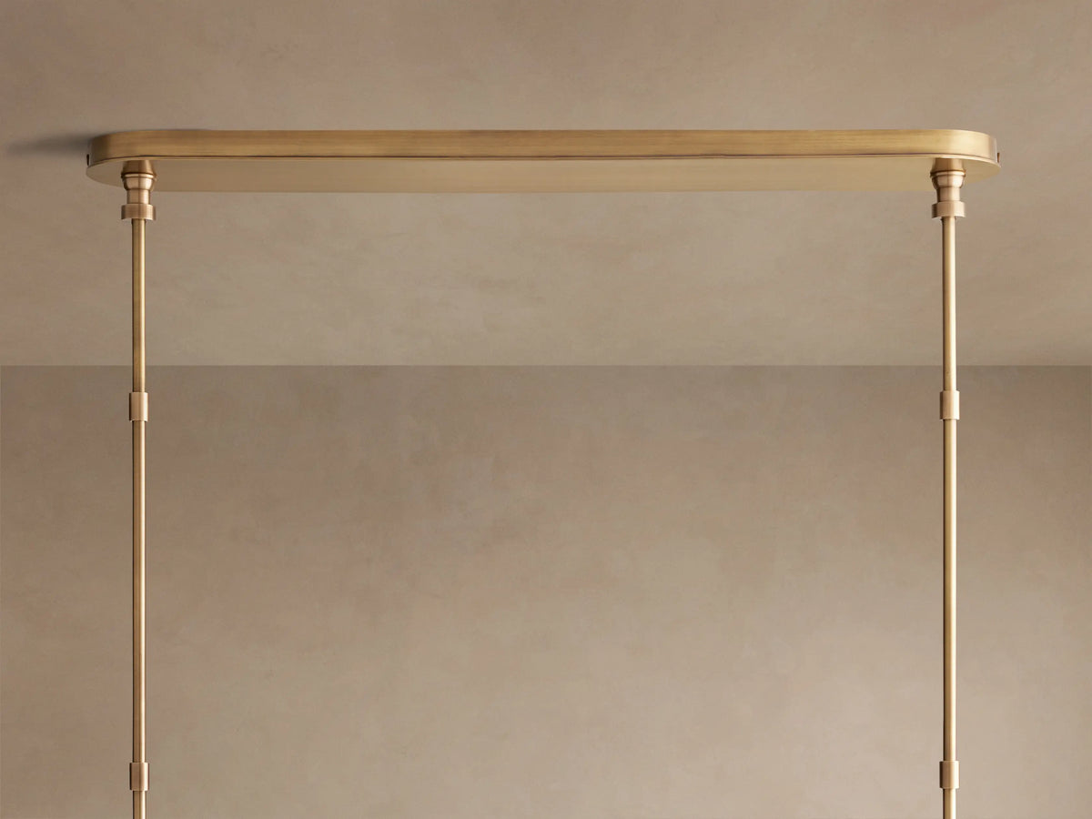 Close-up of Hastings Linear Chandelier with white linen shades, antiqued brass, and brown leather details with white stitching.