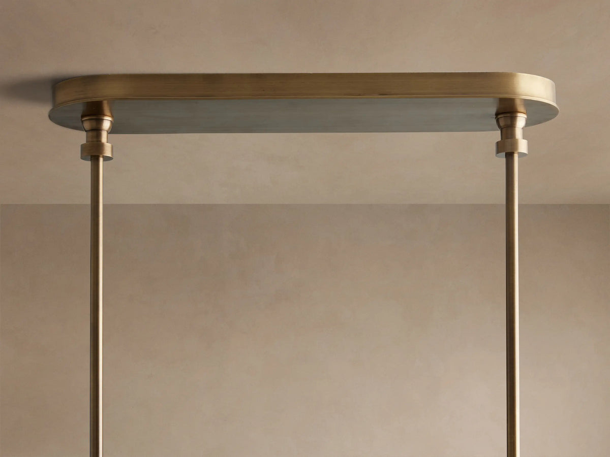 Close-up of Hastings Linear Chandelier, showing brass, brown leather straps with white stitching, and white linen shades.