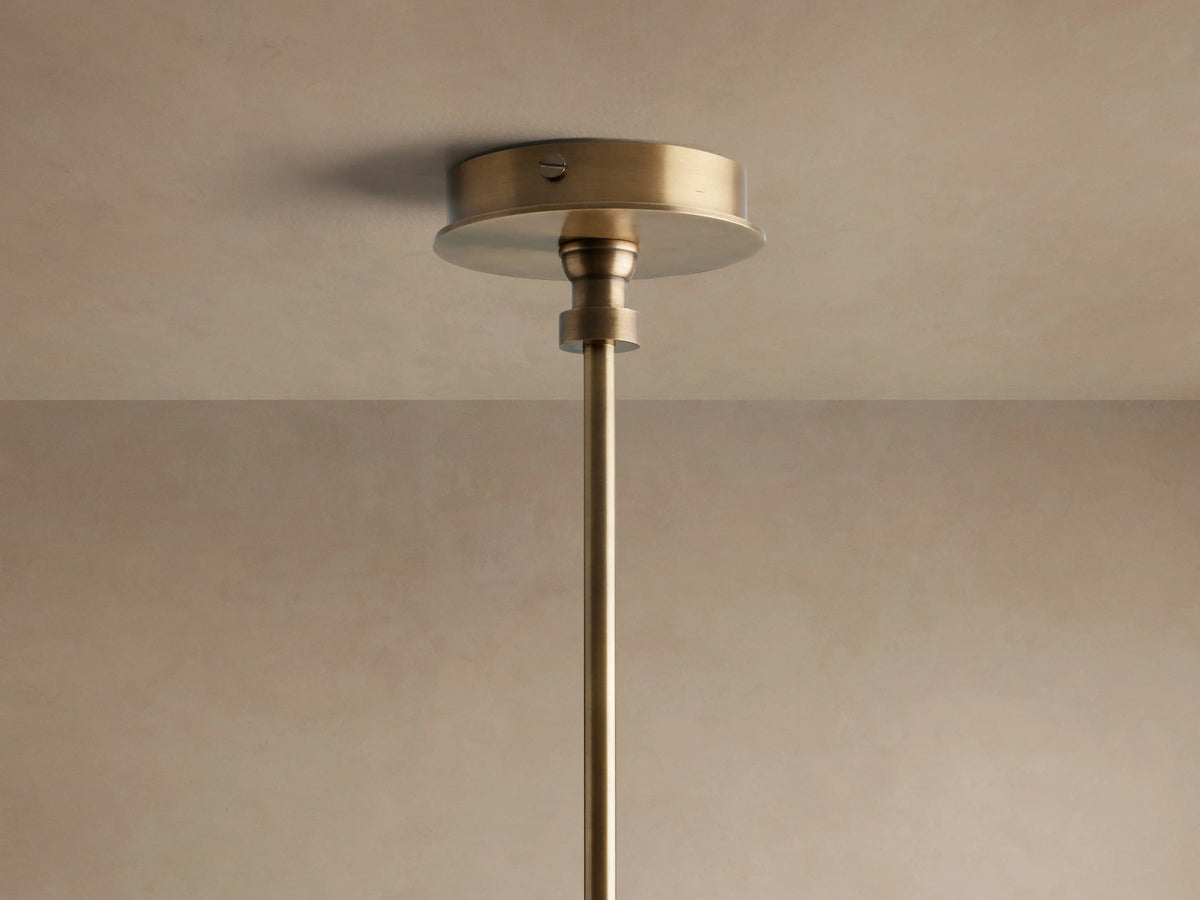 Close-up of Hastings Round Chandelier: antiqued brass frame, tan leather band with stitching, and glowing white linen shades.