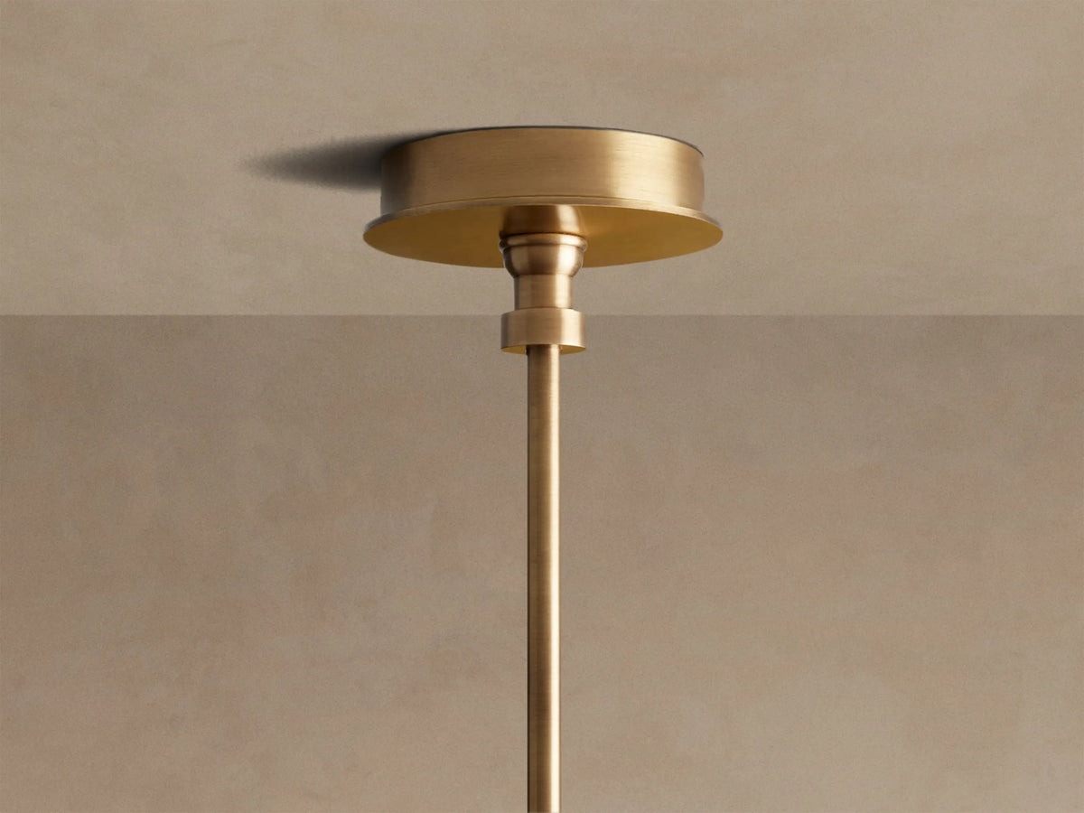 Close-up of the Hastings Round Chandelier, showing antiqued brass, tan leather with stitching, and two lit white linen shades.