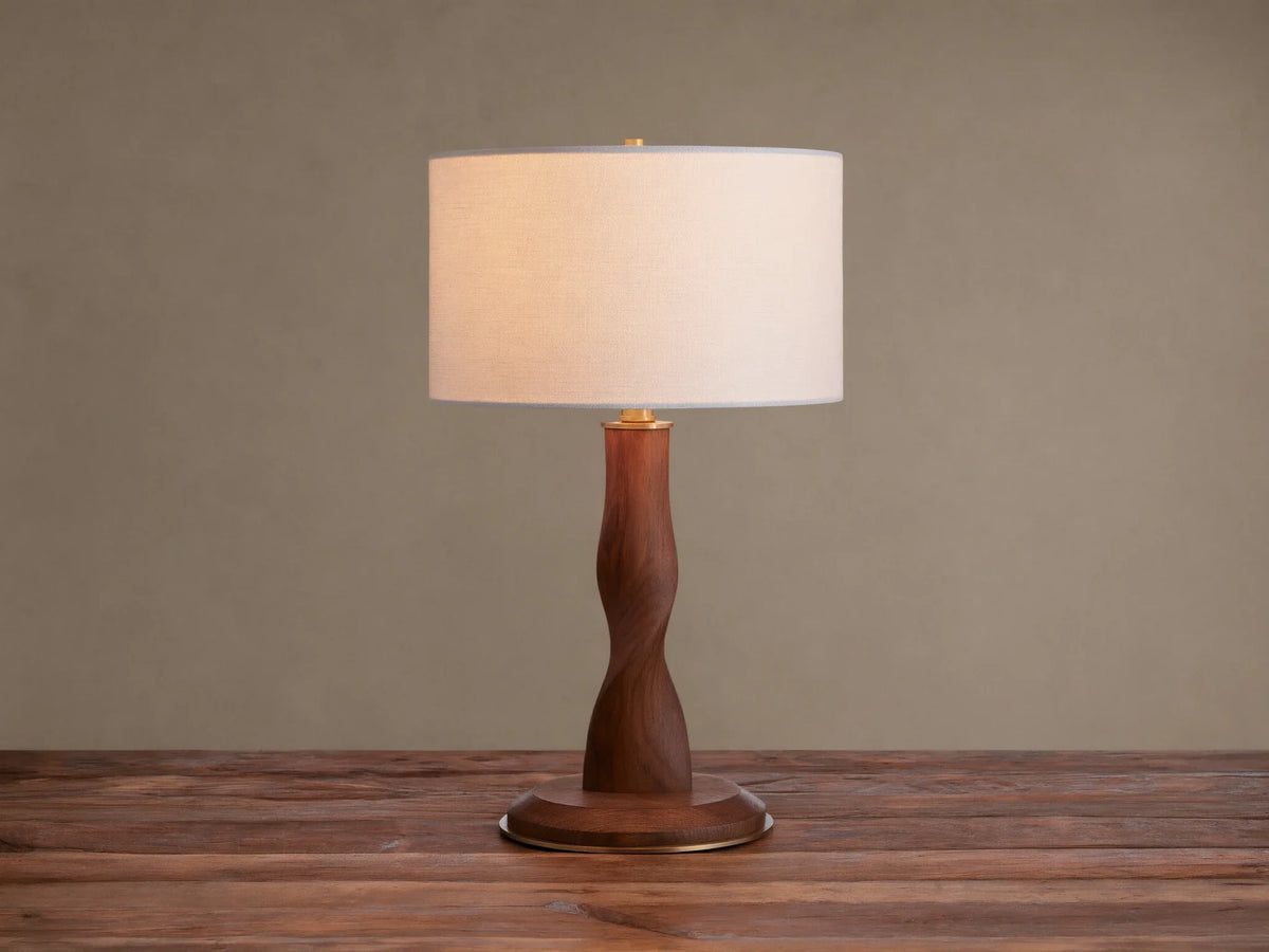 Jonas Table Lamp: Light flax linen shade, dark twisted oak wood stem & base, brass accents, on a rustic wood surface.