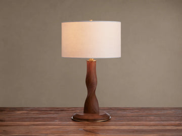 Jonas Table Lamp: Light flax linen shade, dark twisted oak wood stem & base, brass accents, on a rustic wood surface.
