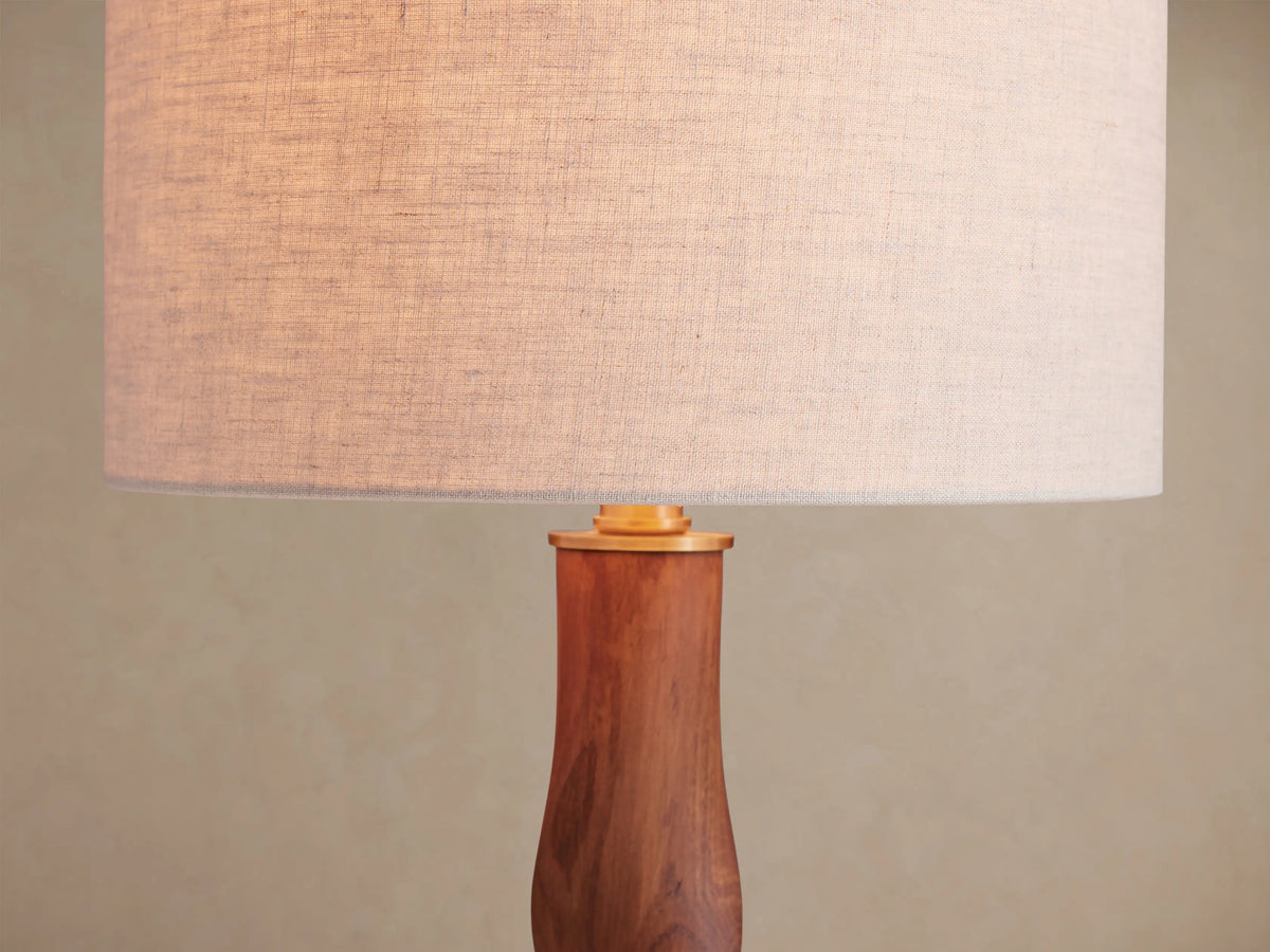 Jonas Table Lamp with light flax linen shade and dark twisted oak wood base, brass accents, on a rustic wooden table.
