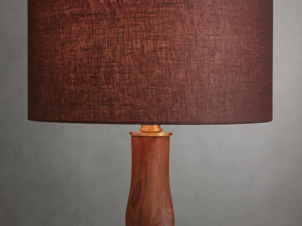 Jonas Table Lamp with a dark brown linen shade and twisted oak wood base, finished with brass accents, on a wooden surface.