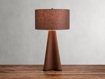 Volant Table Lamp with cone-shaped oak wood base, brass accents, and brown linen shade on a wooden surface.