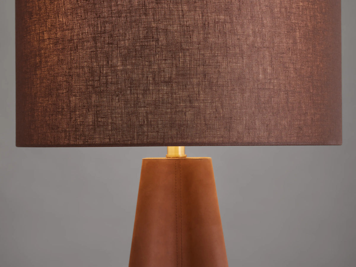 Volant Table Lamp with a conical oak wood base, brown linen shade, and brass accents, on a wooden surface.