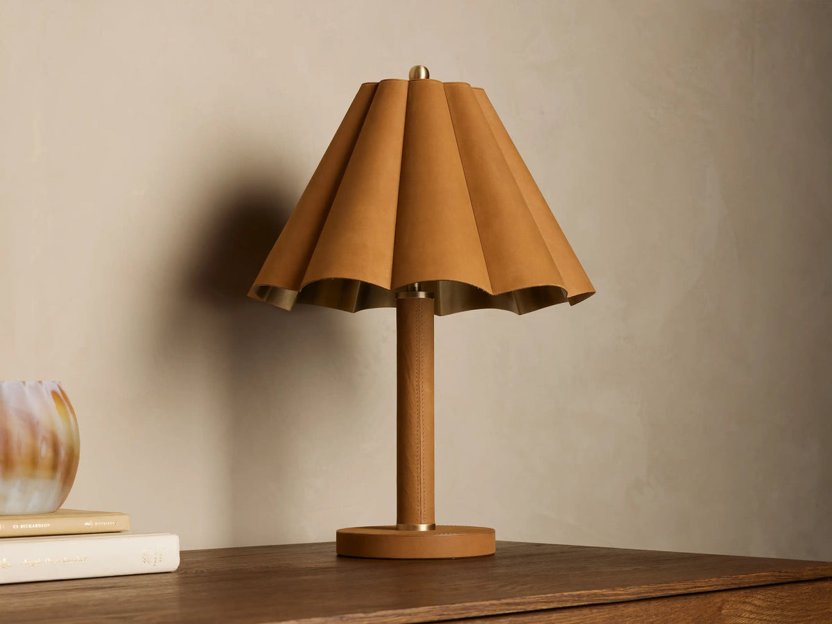 Lucy Accent Table Lamp: pleated camel leather shade with gold lining, leather-wrapped base and stem, brass details, on wood.
