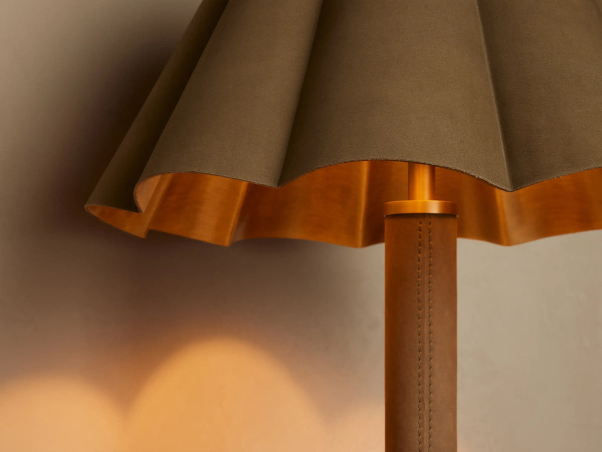 Close-up of Lucy Accent Table Lamp with pleated brown shade, golden interior, and brown leather-wrapped stem. Warm glow.