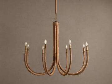 Ravda Round Chandelier features 8 curved rattan arms with brass details, holding glowing clear bulbs, hanging against a brown wall.