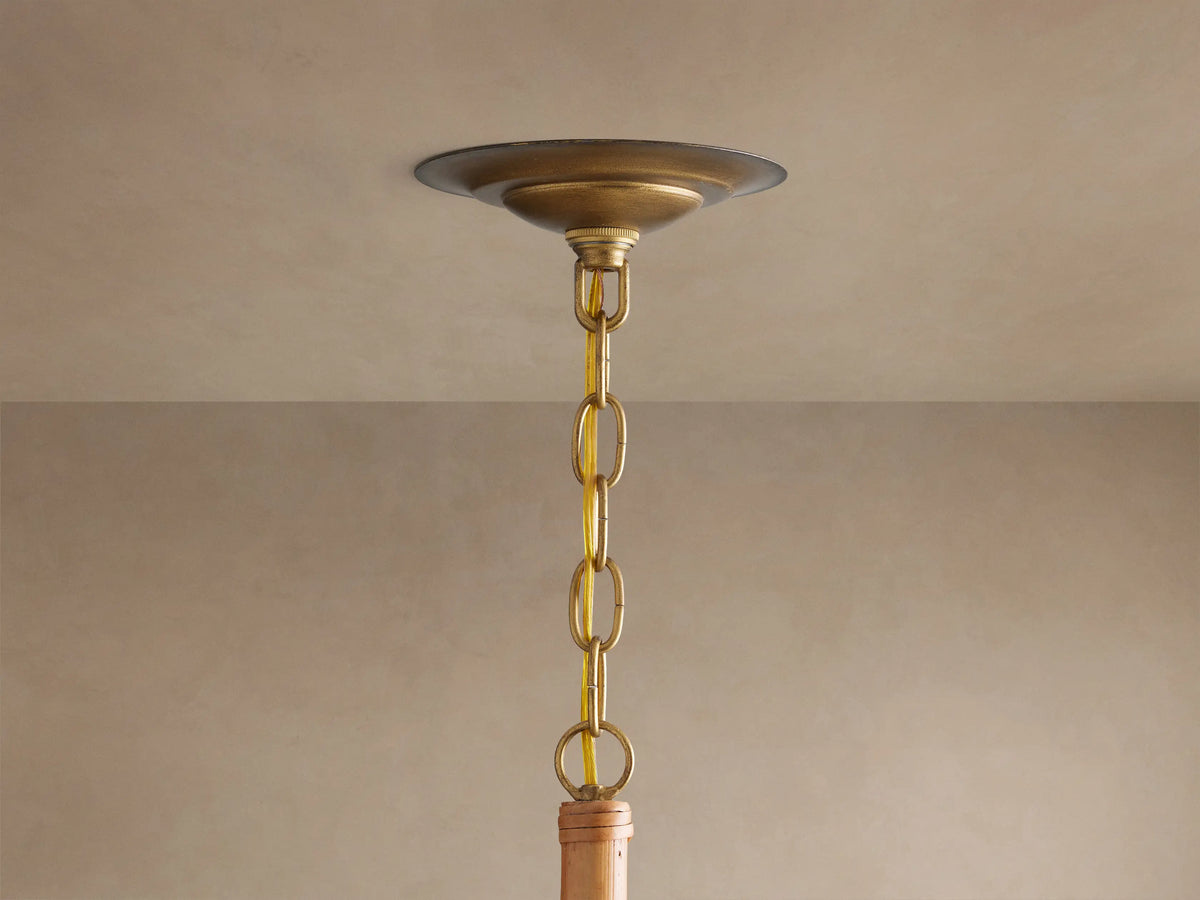 Ravda Round Chandelier's brass ceiling plate, chain, & gold cord hanging from a light beige ceiling.