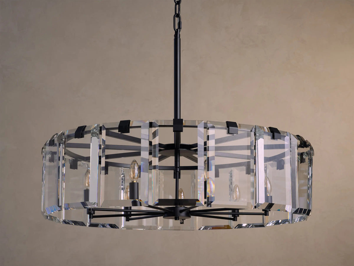 Circular chandelier with black metal frame and clear rectangular glass panels, hanging from a chain against a beige background.
