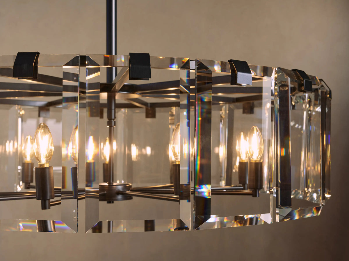 Chandelier with rectangular crystal panels and visible bulbs, emitting warm light. Black metal frame and soft background glow.