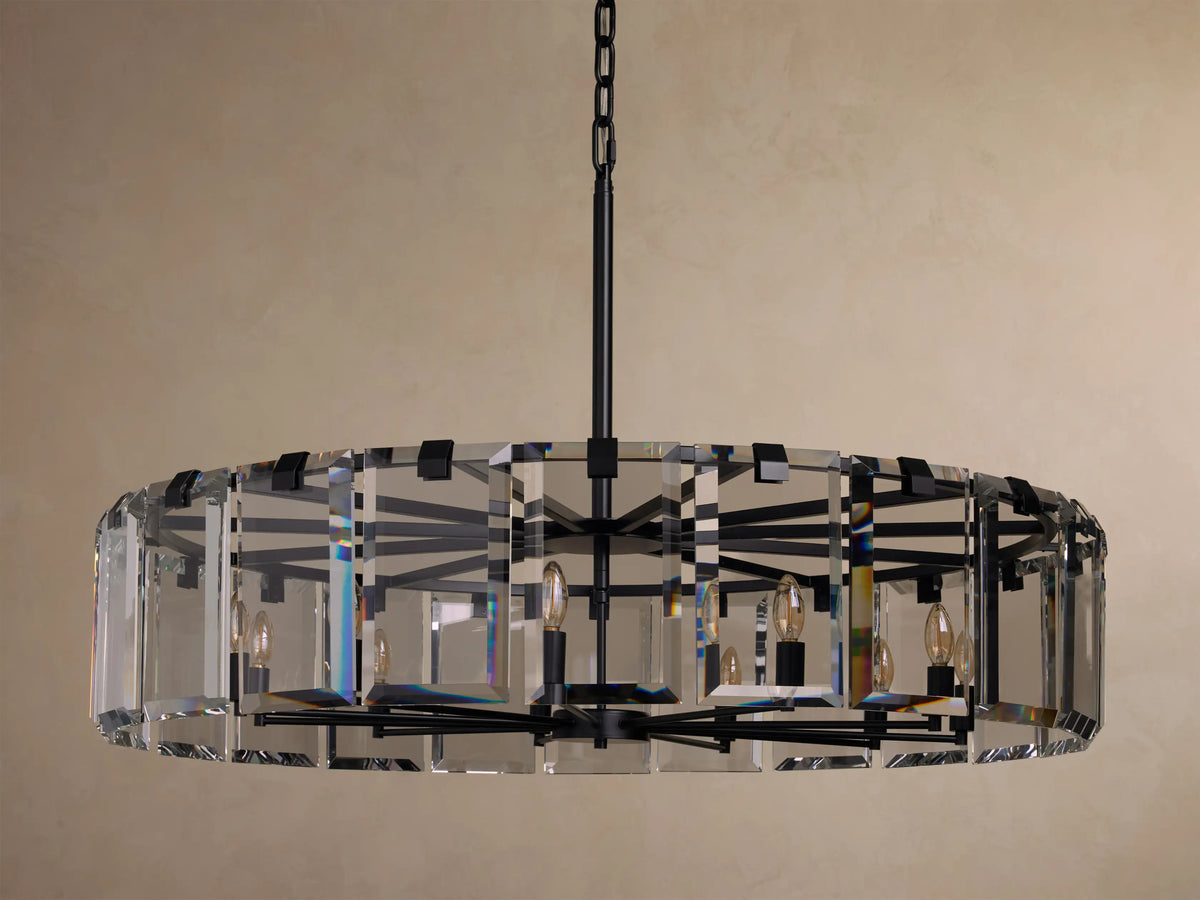 A round chandelier with clear glass panels, black metal frame, and multiple candle-style bulbs, hanging from a black chain.