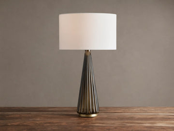 Elisabetta Table Lamp: upright, white linen shade, smoky fluted glass base, brass accent, sitting on a wooden table.