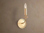 Arnett Sconce: antiqued gold leaf iron sconce with round backplate, curved arm, and candle-style holder with clear bulb.